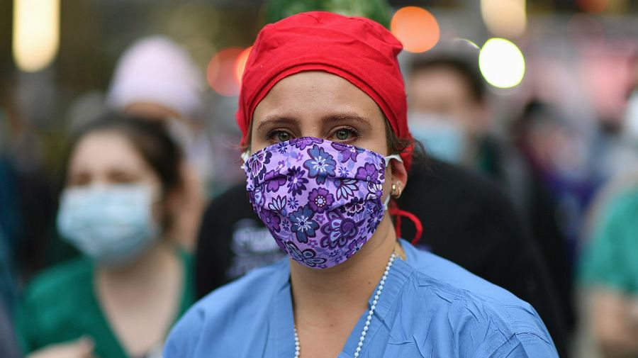 Una trabajadora de salud mira a la gente que aplaudía a los médicos y enfermeras frente a Langone Health Hospital, este jueves en Nueva York.