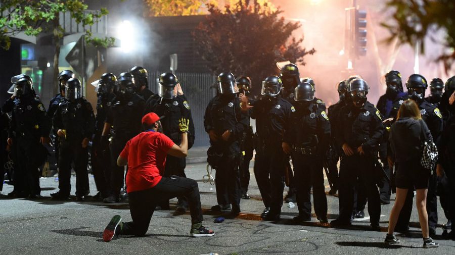 Un hombre se arrodilla ante un grupo de policías, en el medio de las protestas antiracismo en Oakland, California, este viernes 29 de mayo.