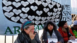 Lucia Zunda Meoqui, sister of Adrian Zunda Meoqui, left, an Argentine Navy officer onboard the ARA San Juan submarine that sank and disappeared on November 15, 2017, cries as she and others chain themselves to the fence of the Casa Rosada.