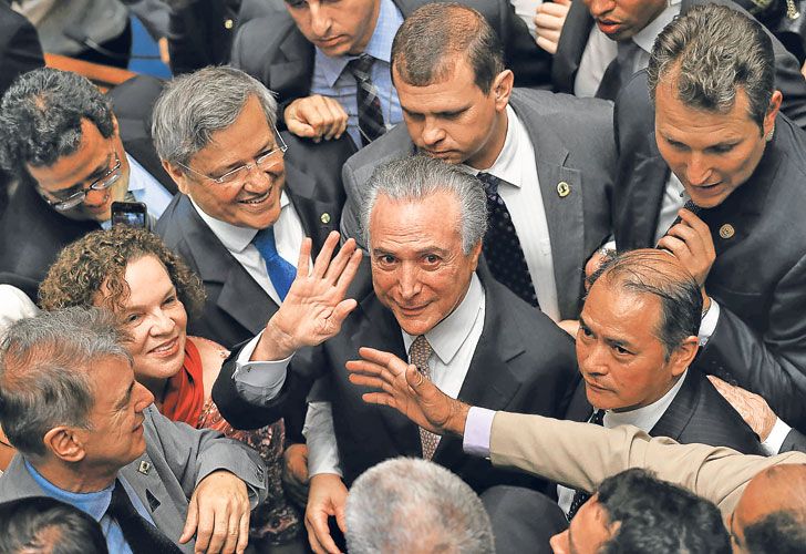 Rodeado. Michel Temer saluda junto a sus asesores antes de asumir la presidencia en forma definitiva. El mandatario carece de una base parlamentaria que apuntale su liderazgo.