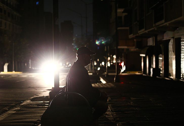 A man sits on a bench in pitch dark, during a power cut in Caracas.