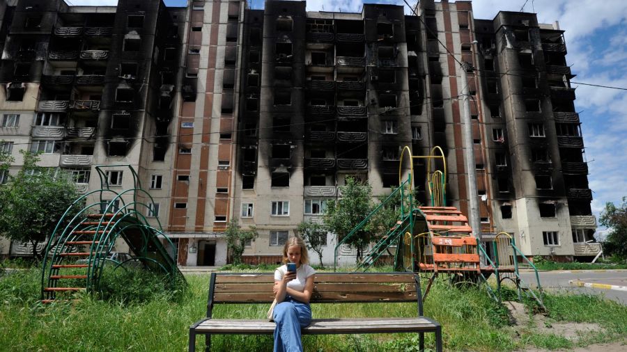 Fotogaleria Una niña mira su smartphone mientras está sentada en un banco frente a los edificios residenciales parcialmente destruidos como consecuencia de los bombardeos en la ciudad de Irpin, cerca de Kiev