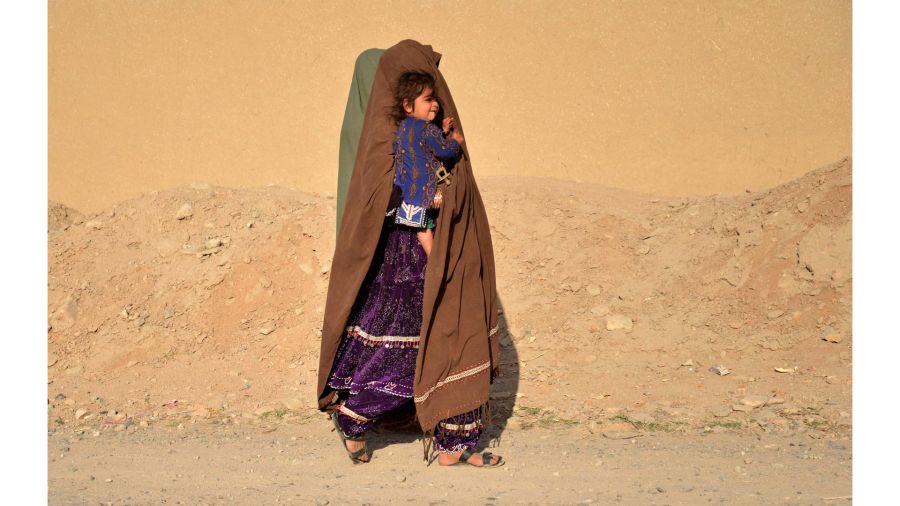 Fotogaleria Una mujer con un niño camina por la banquina de una carretera en el distrito de Zhari, provincia de Kandahar, Afganistán