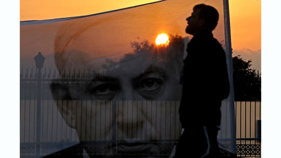Fotogaleria Un manifestante pasa junto a una pancarta que representa al primer ministro israelí, Benjamin Netanyahu, al atardecer frente a la Knesset en Jerusalén
