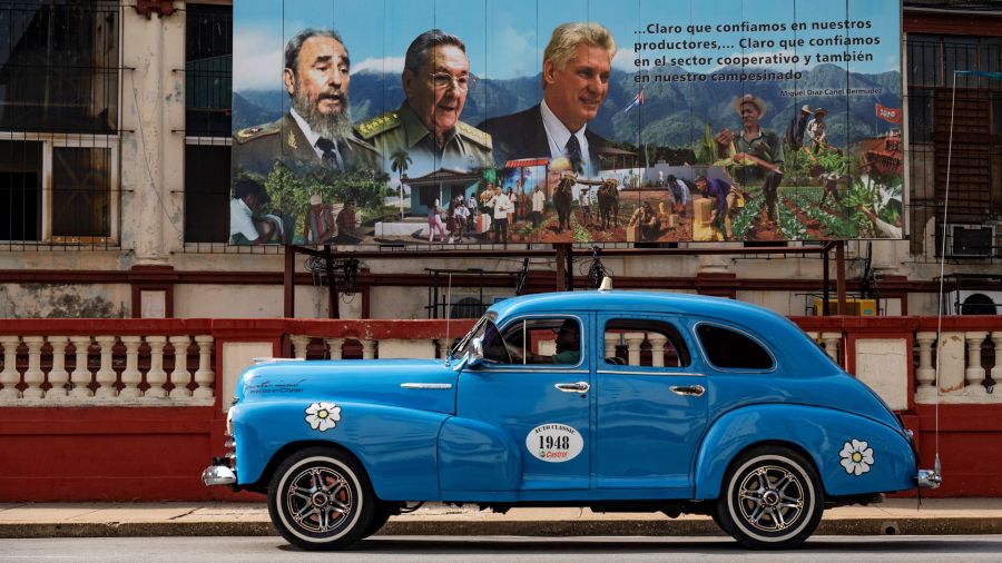 Fotogaleria Un viejo automóvil estadounidense pasa cerca de un cartel del difunto líder cubano Fidel Castro, el expresidente Raúl Castro y el actual presidente Miguel Díaz-Canel en La Habana