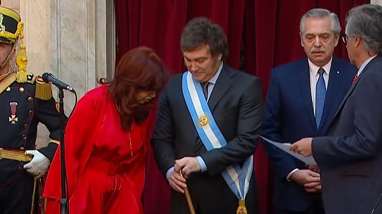 Milei le muestra a Cristina Kirchner el detalle de león en el bastón presidencial.