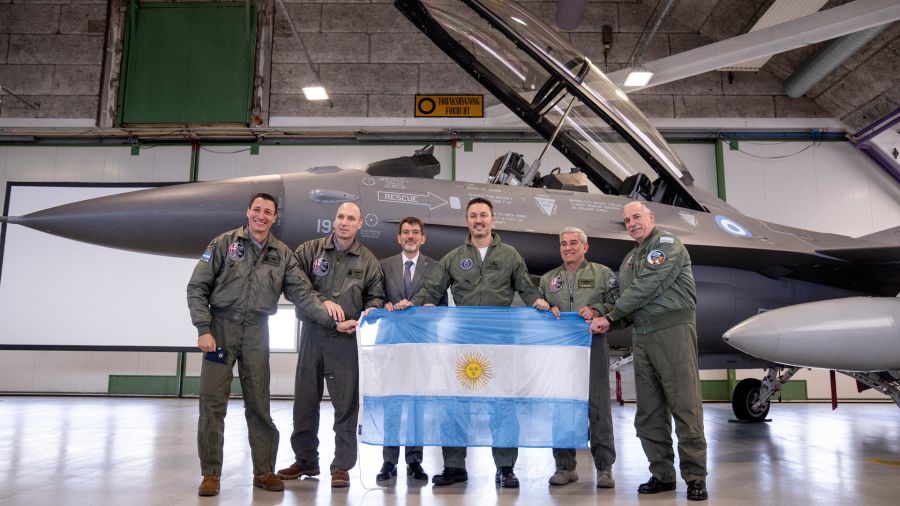Fotogaleria Los miembros de la delegación argentina, incluido el ministro de Defensa, Luis Alfonso Petri, sostienen su bandera nacional mientras posan frente a un caza F-16