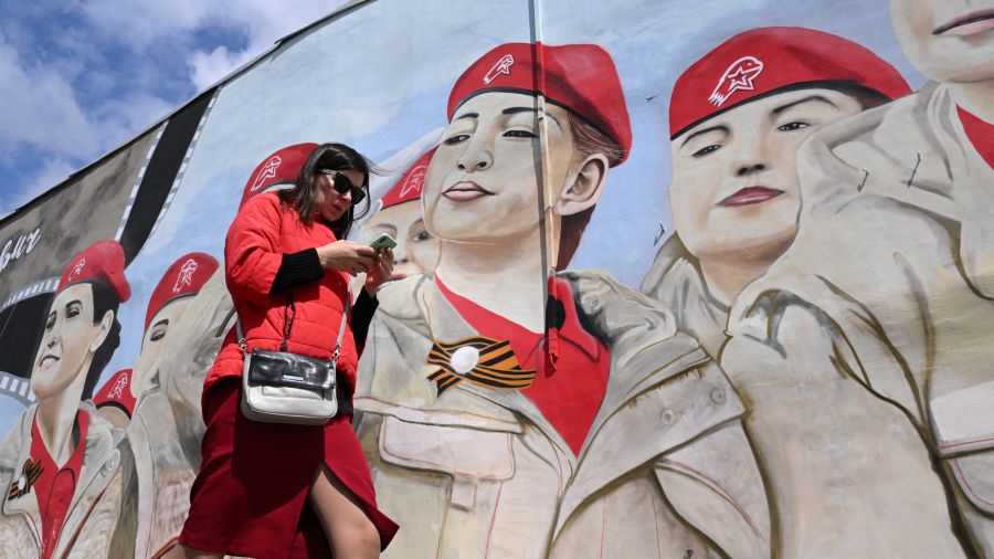 Fotogaleria Una mujer usa su teléfono inteligente mientras pasa junto a un mural que representa a miembros del movimiento patriótico juvenil Yunarmiya (Ejército Joven) de Rusia en Moscú