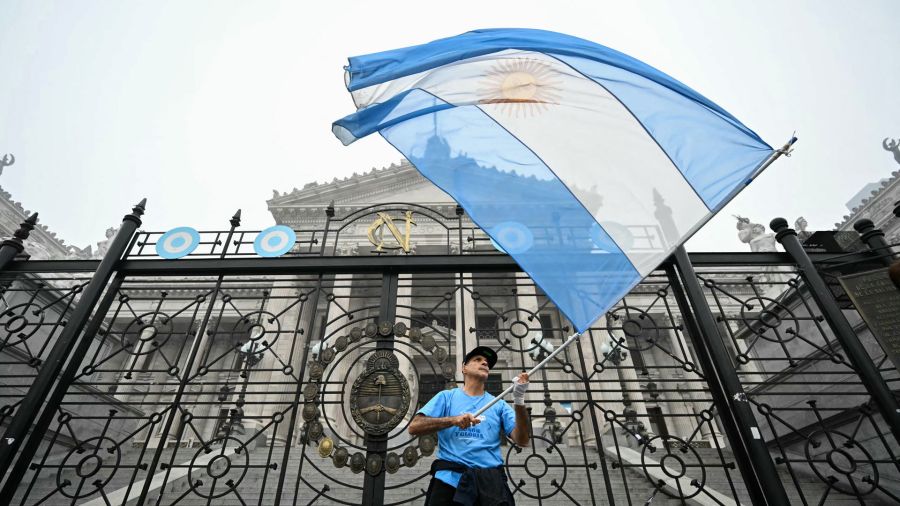 Fotogaleria Un manifestante ondea la bandera argentina frente al Congreso Nacional en Buenos Aires. Los senadores argentinos están discutiendo un paquete de reformas clave para el presidente