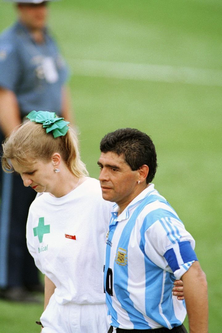 Diego dejando el terreno de juego de la mano de la enfermera. 