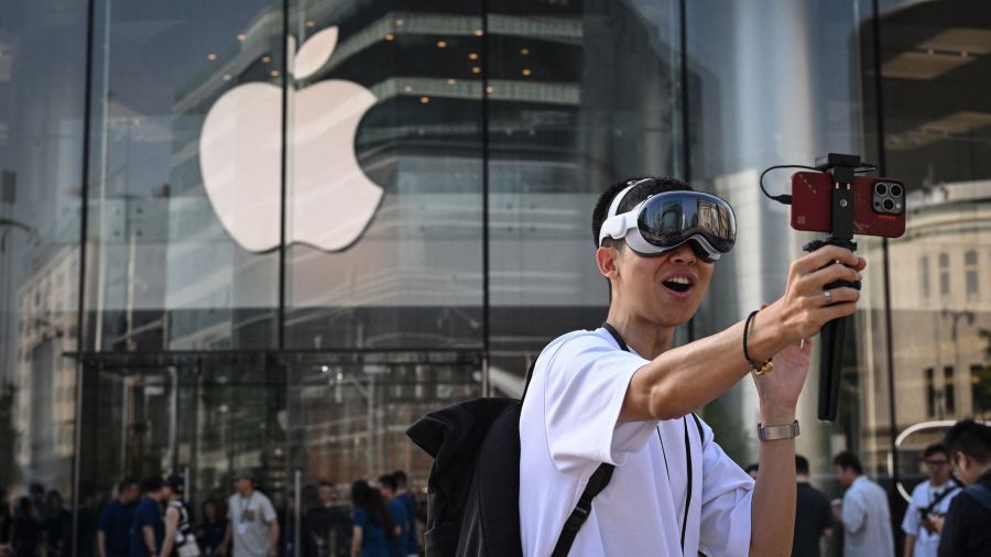 Fotogaleria Un hombre que lleva un casco Apple Vision Pro graba imágenes mientras la gente espera para entrar a la Apple Store durante el lanzamiento del casco de realidad mixta en Beijing