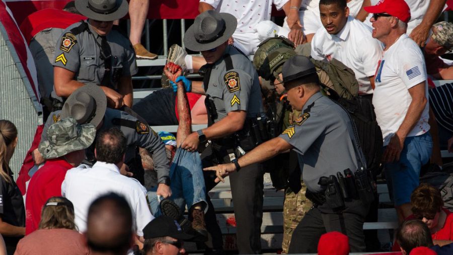 Policías tratan de asistir al espectador del acto de Trump que murió al recibir un disparo en la cabeza.