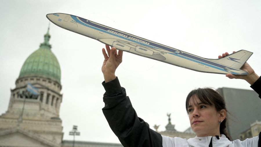 Fotogaleria Un miembro de los sindicatos aeronáuticos sostiene un avión de cartón para protestar contra la privatización de la aerolínea estatal Aerolíneas Argentinas frente al Congreso en Buenos Aires