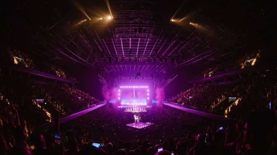 Kylie Minogue regresó a Argentina. La última vez había sido en 2007 y ahora, con 57 años, desplegó un boliche en el estadio Movistar Arena en la que no faltó la bola de espejos, sus bailarines, el multicolor y el papel picado. Ya en los alrededores en la previa se congregaba un público vestido para la fiesta, mucho guiño de comunidad queer que venía a rendir pleitesia a la “Madonna australiana”. Y la artista había estudiado mucho la mística argentina y cumplió con todos los pasos para ser más endiosada aun: aseguró que nunca olvidaría la emoción de esa noche, que nos extraño (mentinos que nos gusta), bailó al son del “olé, olé, olé, olé, Kailiiii Kailiii”, se puso un catsuit que dibujaba la bandera Argentina en lentejuelas, cantó a capela la canción “Where the wild rose grow”, para afirmar que su dueto con Nick Cave lo tiene muy presente. En fin. Kylie Minogue cruzó el océano llena de gloria. Pocos minutos después de las 21 los láseres apuntaban al frente, empezaba la rave de Kylie, que apareció en fucsia charolado como diva y entonó su reciente tema “Lights camera action”. Ya el segundo tema fue un clásico: “In your eyes” y pronto fue el turno de “Come into my world”. Del fucsia Kylie pasó al rojo y preparó al público para cantar “Locomotion”, canción con la que se desplazó entre la gente para pasar a ocupar un escenario desplegado en el centro del lugar. El juego fue honesto, celebrar la nostalgia y el pasado, pero no perder de vista el presente y po eso interpretó “Hold on to now”. Ella no fue la única en cambiar de vestuarios, sus bailarines también pasaron del negro al flúo, al plateado y al dorado. La Kylie es argentina En la segunda parte del concierto Kylie Minogue apareció cubierta de negro, hacía un poco de ruido el vestuario cuando empezó a cantar “Slow”, pero claro, había una sorpresa. A mitad del estribillo se sacó la capa y vestía la bandera de Argentina hecha con lentejuelas. Allí su movimiento y la locura del público se intensificó. No hace falta decir que uno de los platos fuertes del final fue “Can’t get you out of my head” y finalizó el concierto con “Tension”, “Lovers”, Padam” y “Love ar first sight”. Lamento que te lo perdieras, Minogue nos regaló una buena dosis de felicidad. Lista de temas 1. Lights Camera Action / In Your Eyes / Get out of my way / What do I have to do? 2. Come into my world 3. Good as gone / spinning around 4. On a night 5. Last night I dreamt I fell in love 6. Better the devil you know / shocked 7. Dancing 8. Locomotion 9. Hold on to now 10. Wild rose moment 11. (Disco álbum chat into) say something 12. Disco overture 13. Supernova 14. Real Groove 15. Magic / where does the DJ go / Last night a DJ 16. Confide in me 17. Slow 18. Timebomb / EOSN 19. Tension 20. Can´t get you out of my head 21. Lovers 22. Padam 23. In my arms 24. Love at first sight