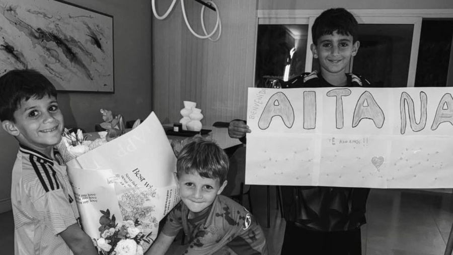 Los hermanos de Aitana celebrando la llegada de su nueva hermanita con un cartel y flores.
