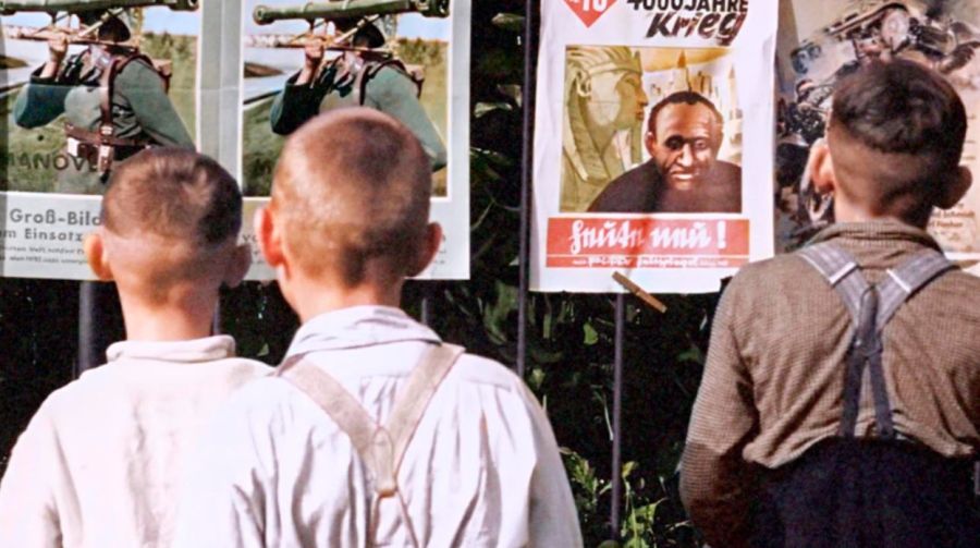 Niños alemanes observan el periódico antisemita Der Stürmer y otros carteles de propaganda nazi