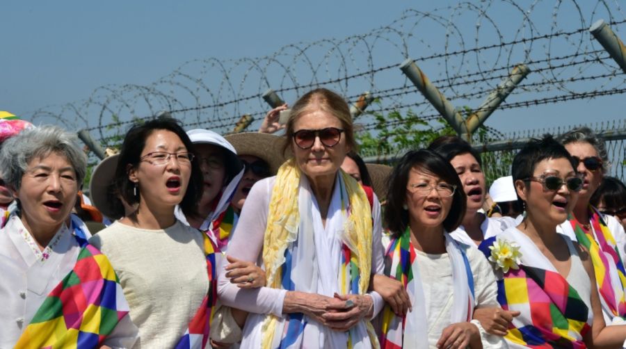 Gloria Steinem y activistas por la paz surcoreanos marchan junto a una valla militar en un puesto de control en Paju el 24 de mayo de 2015