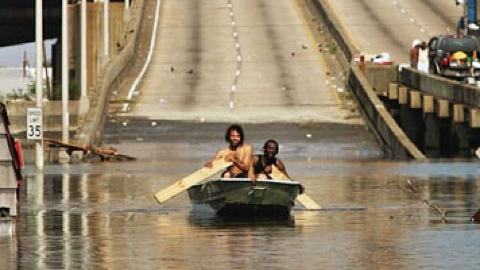 Dos personas cruzan con un bote cerca de uno de los puentes de Nueva Orleáns
