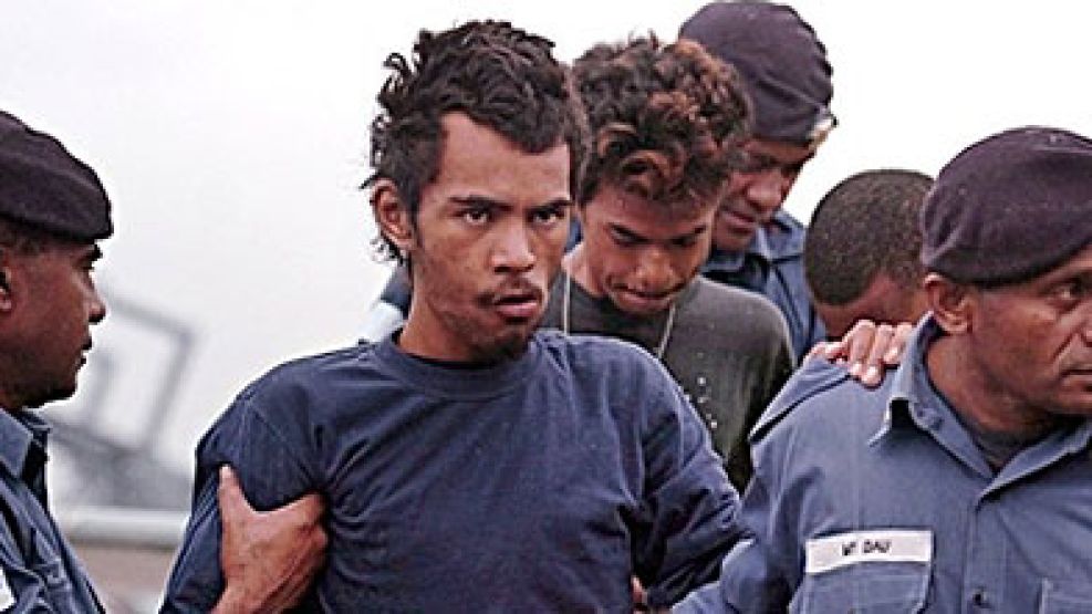 Dos de los jóvenes rescatados en el Pacífico, Filo Filo y Samuel Perez, acompañados por soldados fidjianos al llegar a la base naval de Suva.