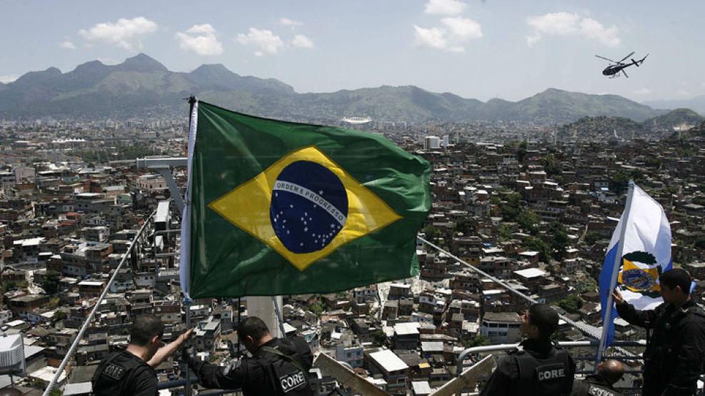 Policías y miembros del Ejército, colocan una bandera de Brasil en la cima del morro tras "conquistar" la favela Alemão