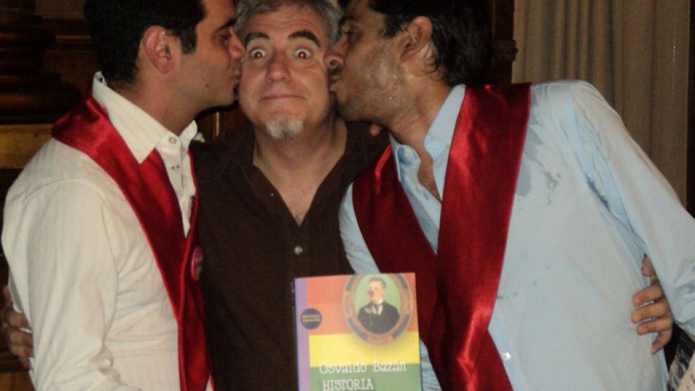 Alex Freire y José María di Bello saludan a Osvaldo Bazán en la presentación del Libro.
