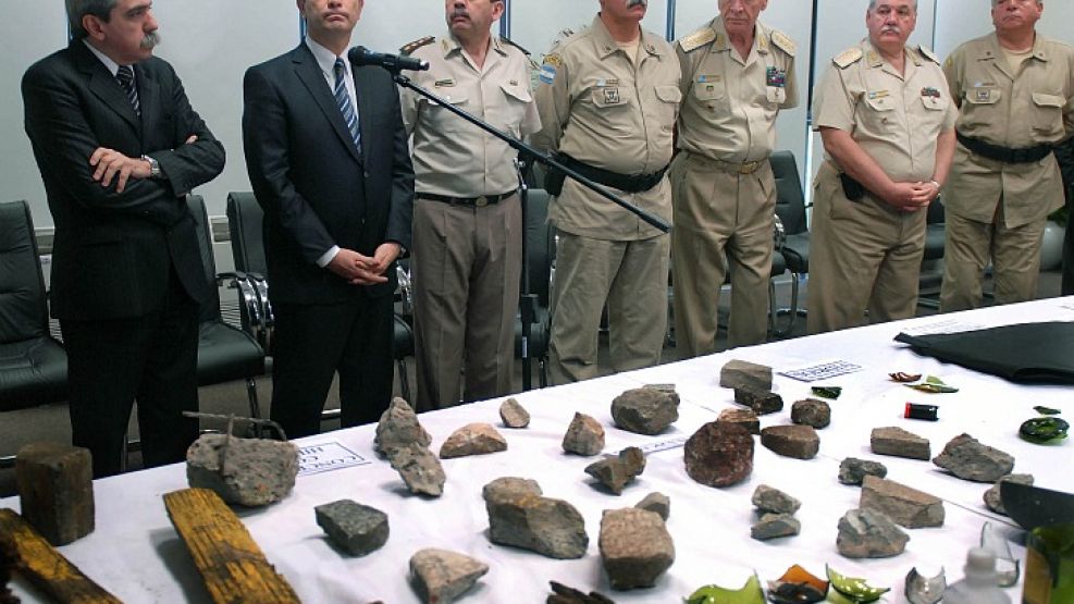 Aníbal Fernández, Julio Alak y miembros de las fuerzas de seguridad. El jefe de Gabinete le mostró a los medios los cascotes y los palos de los okupas.