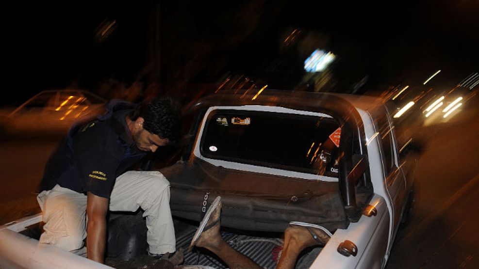 El delicuente muerto y esposado en la caja de una camioneta de la policía bonaerense.