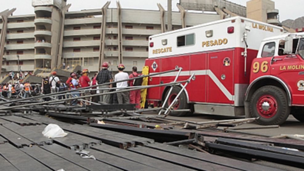 Los bomberos trabajan entre los hierros de la tribuna que se derrumbó en Perú.