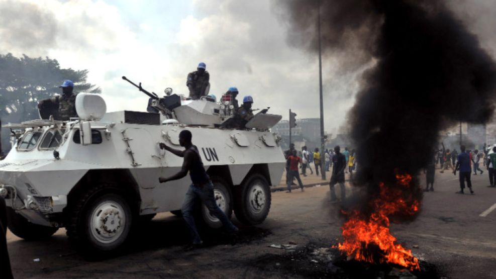 Un tanque de la ONU cruza un grupo de manifestantes que apoyan a Ouattara.