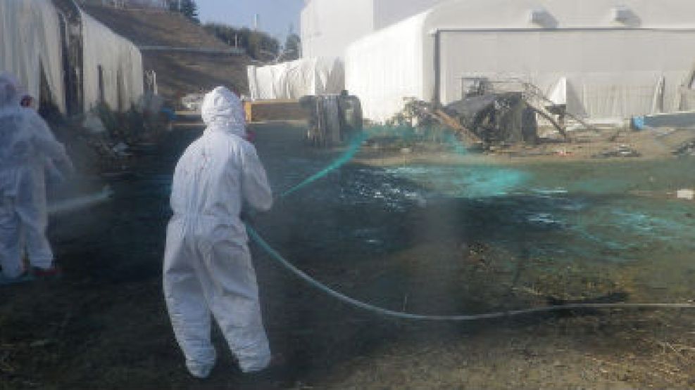 Trabajadores riegan resina verde a base de polvo protector en el área de una piscina dañada.