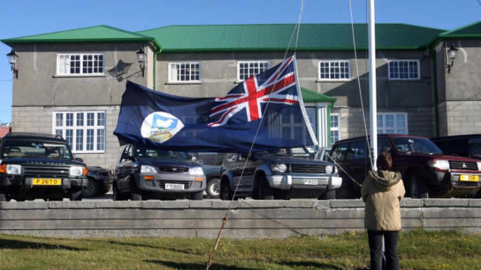 Un empleado administrativo estatal de Malvinas iza la bandera kelper.