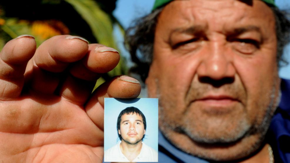 El padre de Miguel, el joven de 32 años que falleció después de ser golpeado por una bengala, sostiene la foto de su hijo en mayo del año pasado. 