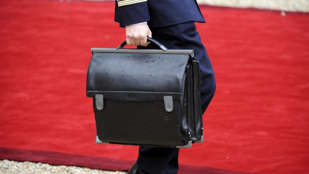 Un oficial acompaña a Hollande junto al "famoso" maletín con los códigos nucleares.