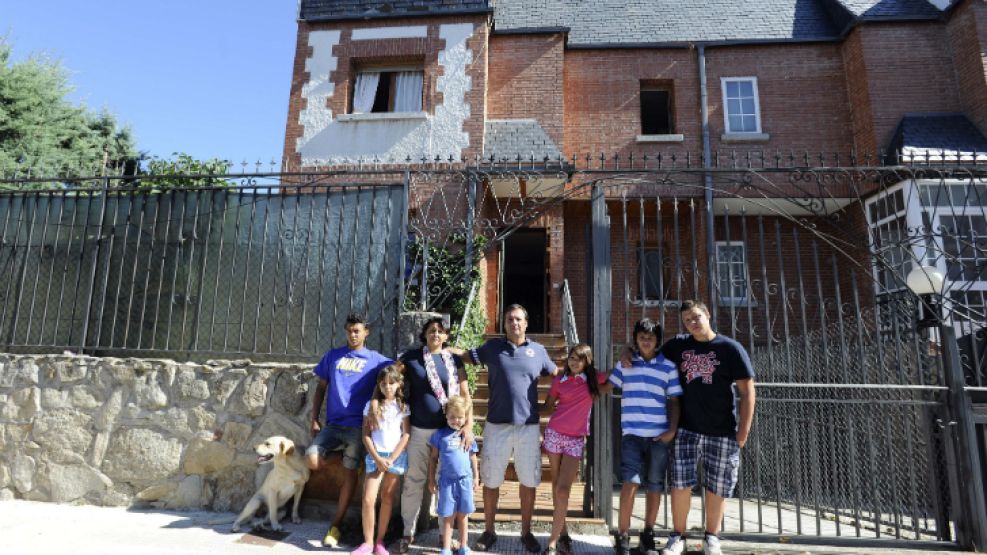 Ocupas argentinos. Raúl Maneiro y Andrea Garrone, junto a sus ocho hijos y su perro, frente a la casa que estaba deshabitada. Entraron por la ventana y se colgaron de la luz.