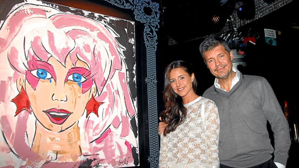 Orgulloso. El conductor con su hija delante de uno de los cuadros que componen la expo que Candelaria realizó el jueves. Tinelli tiene una obra de ella en su camarín.