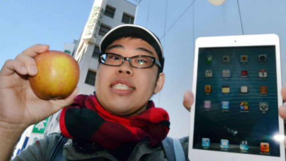 Un japonés sostiene su iPad Mini y una manzana en Tokio.