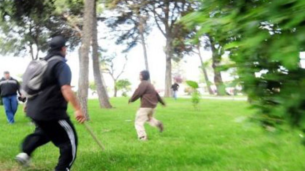 Un chico es perseguido por un hombre para ser atacado con un palo.