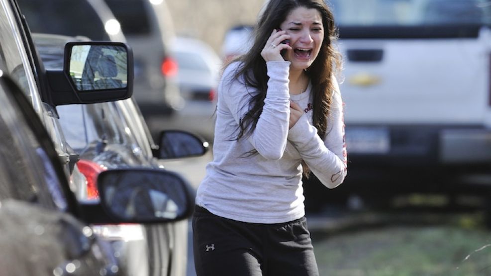 Una mujer llora mientras habla por teléfono en las afueras de la escuela.