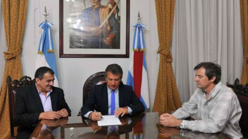 El gobernador entrerriano Sergio Urribarri, acompañado por su vicegobernador,  firmando la normativa que prohíbe el funcionamiento de prostíbulos.