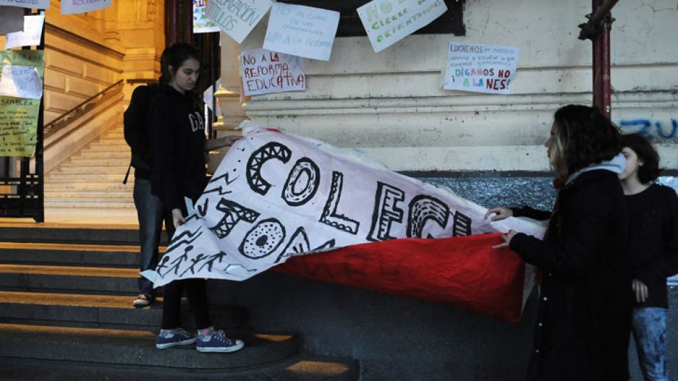 Alumnos del Nacional de Buenos Aires retiran los afiches colocados en la fachada de la escuela. Prometieron encargarse de la limpieza.