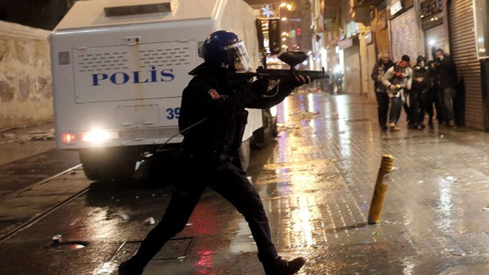 Ataque. Un policía dispara contra los manifestantes en una de jornada cargada de violencia.