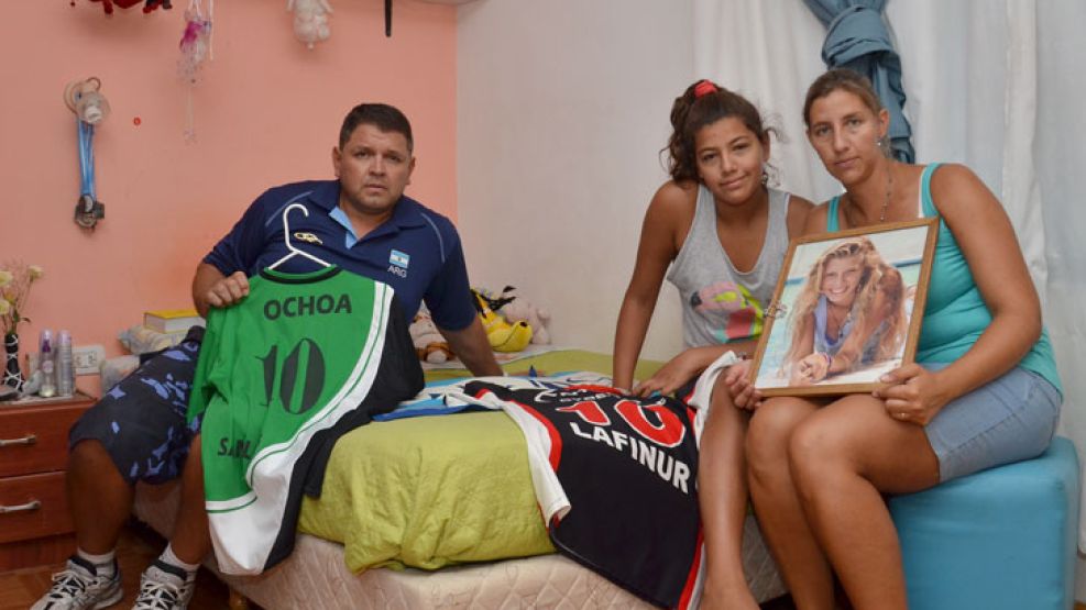 Recuerdos. Fabián Ochoa; su mujer, Valeria, y su hija Salma posan en el cuarto de Priscila, con sus camisetas de voley y sus fotos.