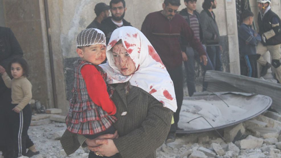 Dolor. Una mujer herida carga a su hijo en brazos en Alepo.