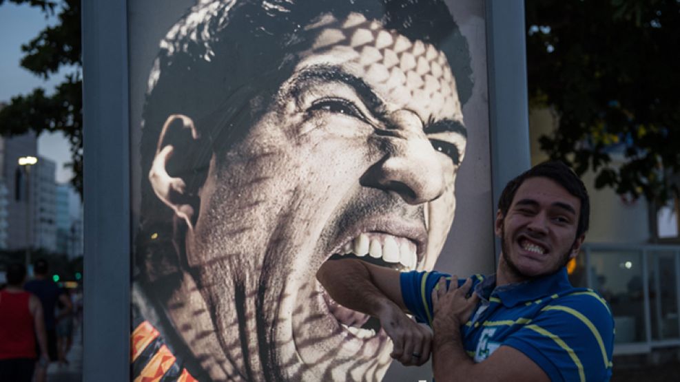 Diente por diente. Un turista juega con la imagen de Suárez en la playa de Copacabana, en Río de Janeiro.