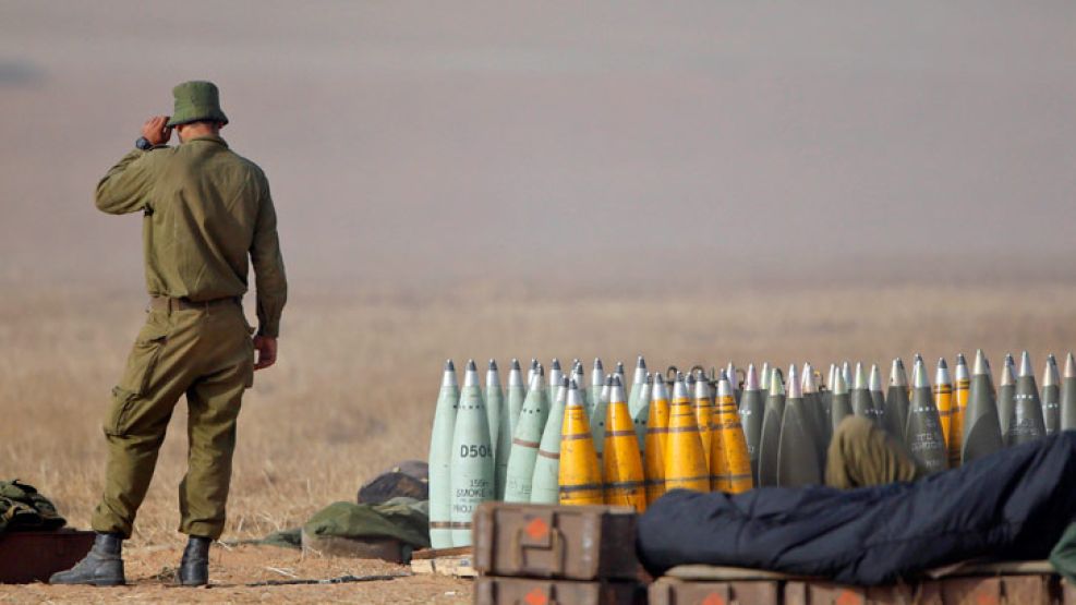 Armado. Un soldado israelí custodia un arsenal en la frontera con la Franja de Gaza, donde 40 mil reservistas fueron apostados.