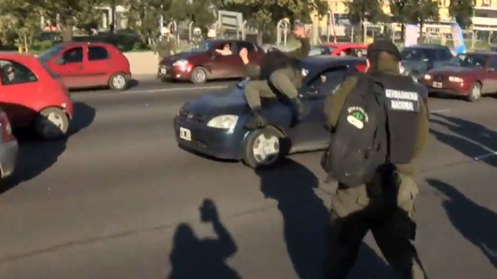 El momento en el que el gendarme se tira encima del auto.