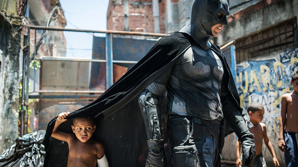 Unos niños juegan en torno a un hombre disfrazado de Batman en la Favela do Metro, cerca del estadio Maracaná en Río de Janeiro.