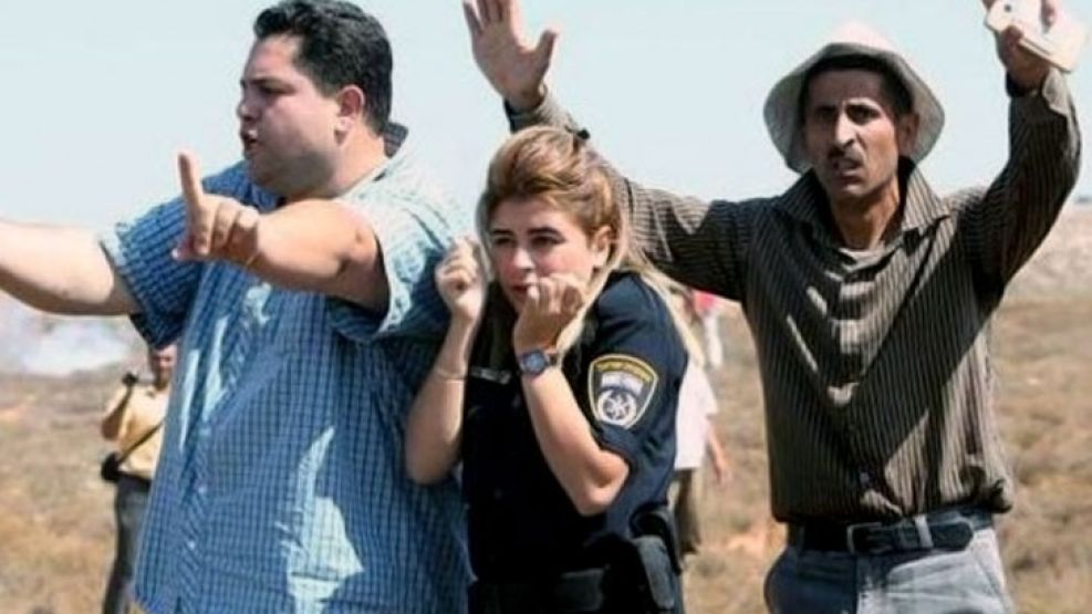 Dos hombres palestinos protegen del lanzamiento de piedras a una oficial de policía israelí. Fuente: Twitter