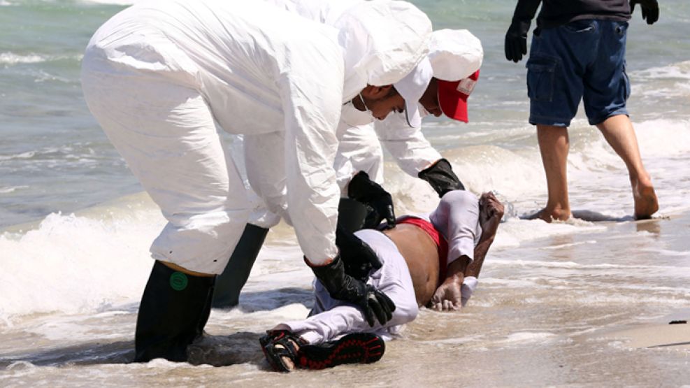 Desesperanza. Voluntarios recogen el cadáver de un inmigrante ahogado en las costas de Libia. Un refugiado sirio es detenido en la frontera entre Serbia y Hungría.