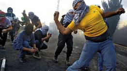 Violencia. Jóvenes palestinos arrojan piedras en la valla que separa Gaza de Israel.